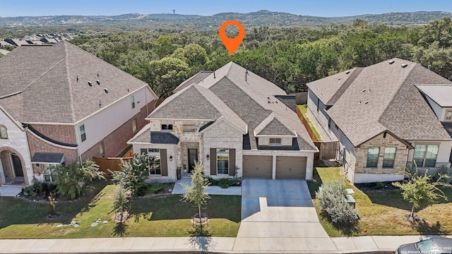 9032 Raven Pointe, San Antonio, TX 78255 - view of front of house featuring concrete driveway, stone siding, and a wooded view