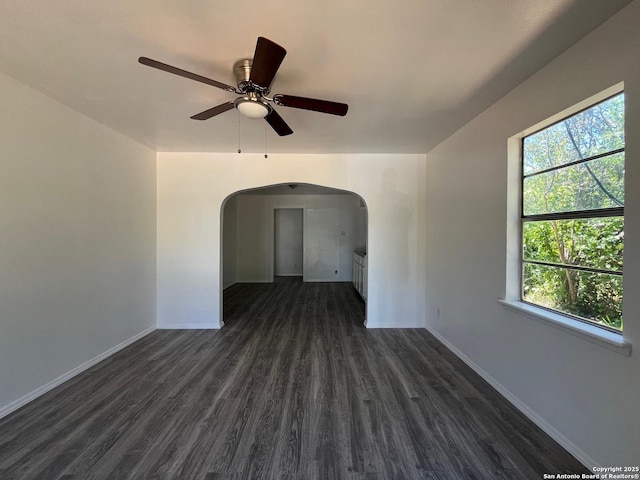 130 N Trevino, Pearsall, TX 78061 - spare room featuring arched walkways, a ceiling fan, and dark wood-style flooring