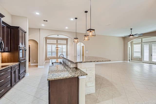 3342 Harvest, Marion, TX 78124 - kitchen with arched walkways, light tile patterned floors, healthy amount of natural light, an island with sink, and recessed lighting