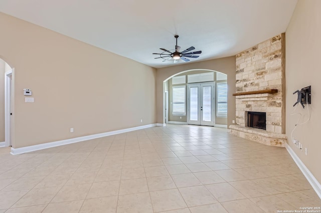 3342 Harvest, Marion, TX 78124 - unfurnished living room with arched walkways, ceiling fan, a stone fireplace, and light tile patterned floors