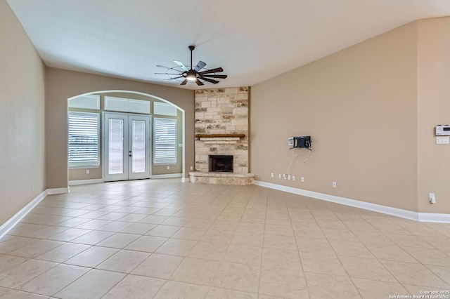 3342 Harvest, Marion, TX 78124 - unfurnished living room featuring a ceiling fan, french doors, light tile patterned floors, arched walkways, and a stone fireplace