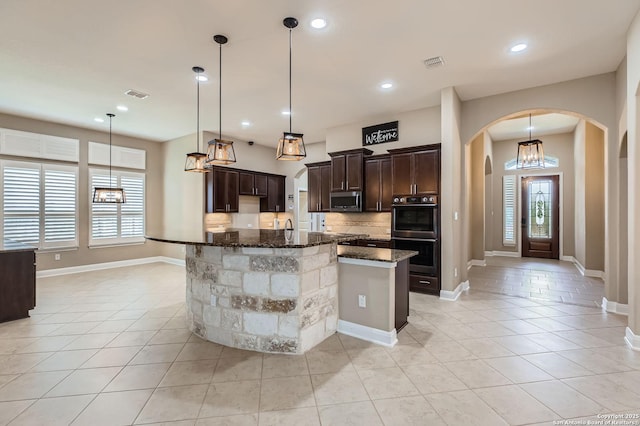 3342 Harvest, Marion, TX 78124 - kitchen with arched walkways, stainless steel appliances, tasteful backsplash, dark brown cabinets, and dark stone countertops