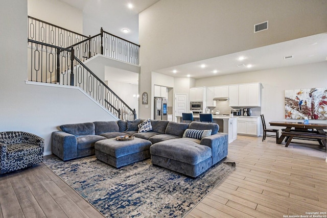 12108 Buckaroo Rnch, San Antonio, TX 78254 - living room featuring light wood-style flooring, stairs, a high ceiling, and recessed lighting