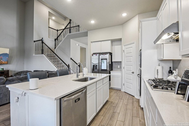 12108 Buckaroo Rnch, San Antonio, TX 78254 - kitchen featuring appliances with stainless steel finishes, wall chimney range hood, open floor plan, tasteful backsplash, and light wood-type flooring
