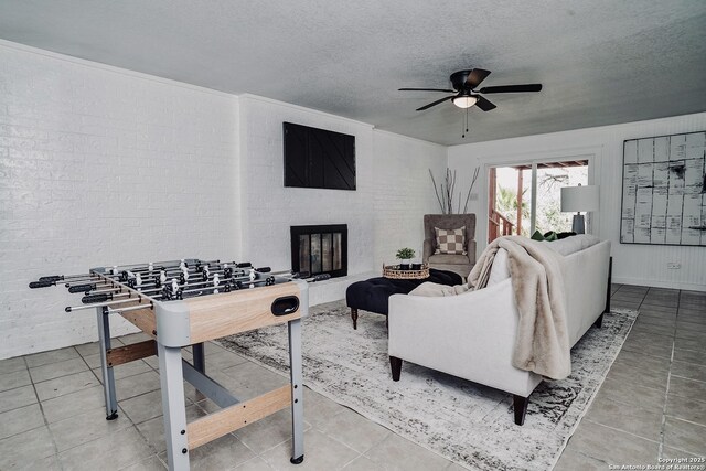 140 Riverview Rd, Mcqueeney, TX 78123 - living room featuring a ceiling fan, a textured ceiling, a glass covered fireplace, and brick wall