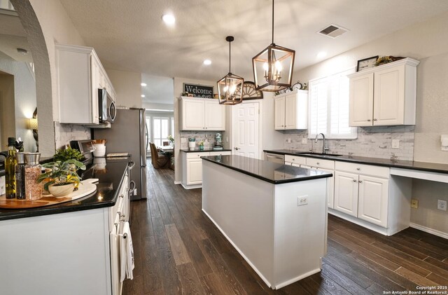21539 Bubbling Crk, San Antonio, TX 78259 - kitchen with dark countertops, appliances with stainless steel finishes, a kitchen island, white cabinetry, and dark wood-type flooring