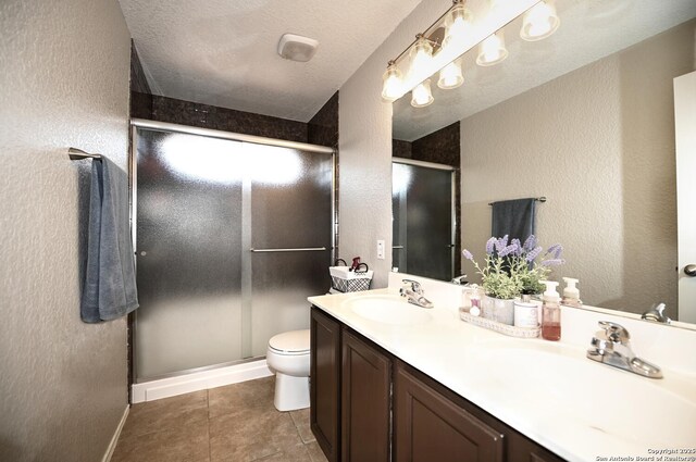 21539 Bubbling Crk, San Antonio, TX 78259 - bathroom featuring double vanity, a textured wall, a stall shower, tile patterned floors, and a textured ceiling