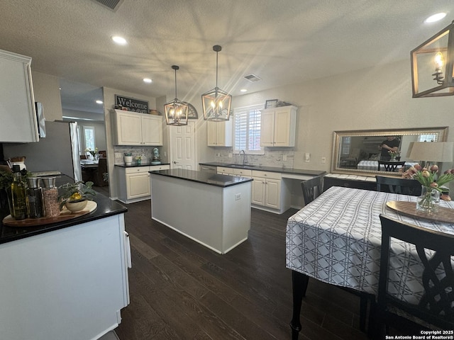 21539 Bubbling Crk, San Antonio, TX 78259 - kitchen with a chandelier, dark wood-style flooring, white cabinets, dark countertops, and tasteful backsplash