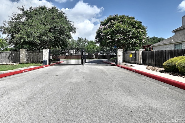 21539 Bubbling Crk, San Antonio, TX 78259 - view of asphalt road with sidewalks, a gate, a gated entry, and curbs