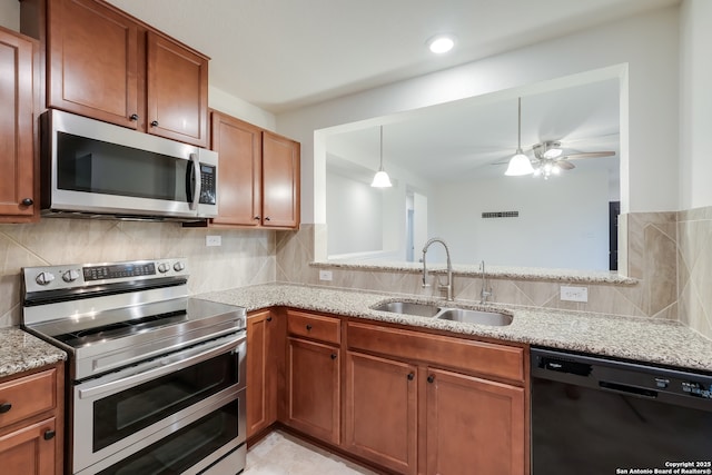 8438 Cordova Pt, San Antonio, TX 78252 - kitchen featuring appliances with stainless steel finishes, brown cabinetry, light stone countertops, and ceiling fan