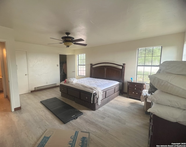 179 Cherry Springs Rd, Hunt, TX 78024 - bedroom featuring a baseboard heating unit, light wood-style floors, a ceiling fan, and a walk in closet