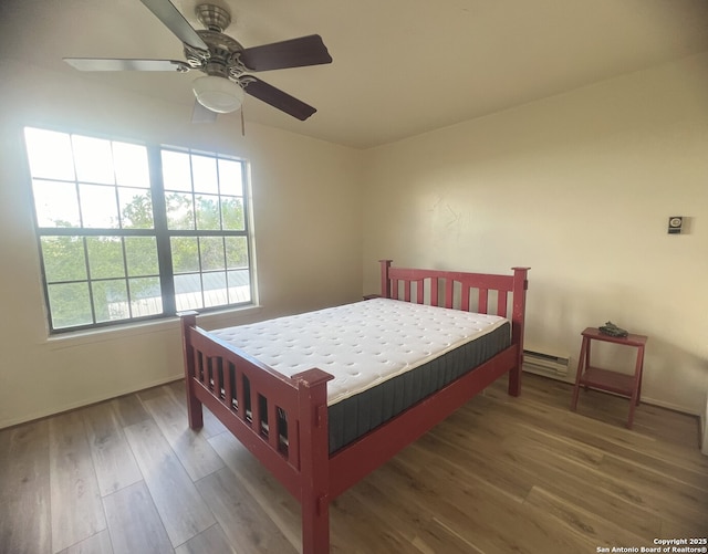 179 Cherry Springs Rd, Hunt, TX 78024 - bedroom featuring wood finished floors, a baseboard heating unit, and a ceiling fan