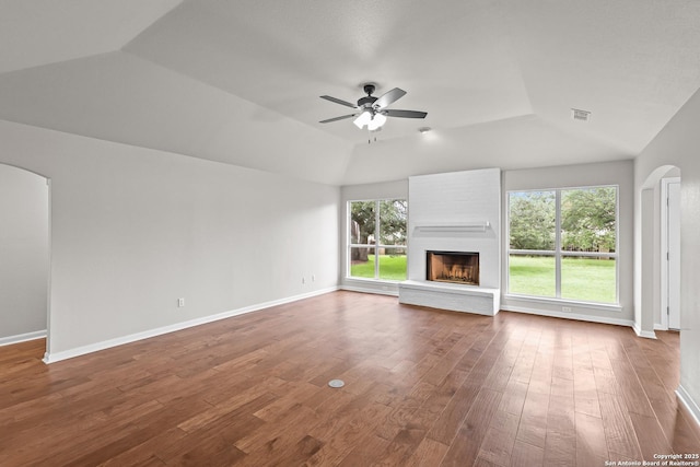 29732 Cojak Cir, Boerne, TX 78015 - unfurnished living room featuring arched walkways, ceiling fan, vaulted ceiling, wood finished floors, and a large fireplace