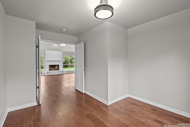 29732 Cojak Cir, Boerne, TX 78015 - empty room with dark wood-style floors, a fireplace with raised hearth, ceiling fan, and a smoke detector