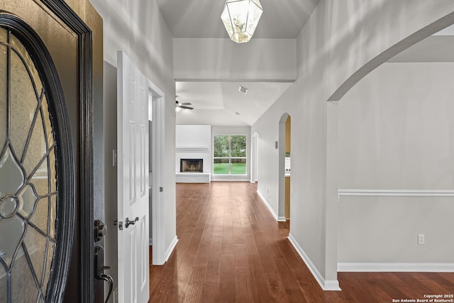 29732 Cojak Cir, Boerne, TX 78015 - foyer featuring dark wood-type flooring, a fireplace with raised hearth, a ceiling fan, and arched walkways