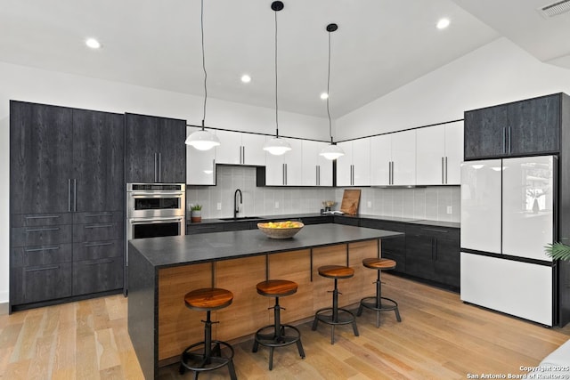 238 Cassiano St, San Antonio, TX 78204 - kitchen featuring freestanding refrigerator, double oven, dark countertops, a kitchen breakfast bar, and a kitchen island