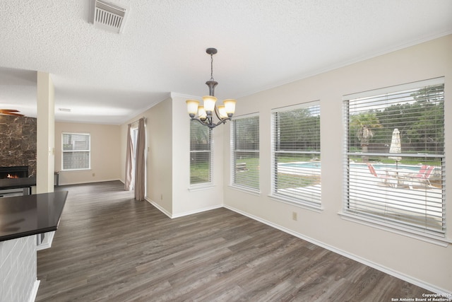 18706 Redriver, San Antonio, TX 78259 - unfurnished dining area featuring a chandelier, dark wood-style flooring, a large fireplace, ornamental molding, and a textured ceiling