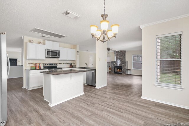 18706 Redriver, San Antonio, TX 78259 - kitchen with appliances with stainless steel finishes, dark countertops, open floor plan, a center island, and white cabinets