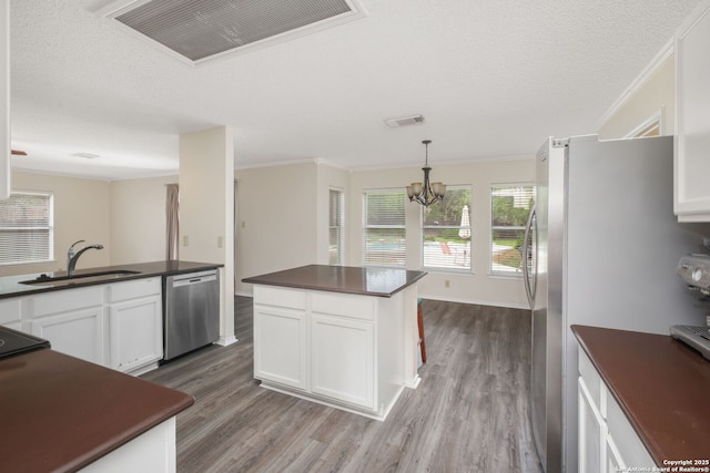 18706 Redriver, San Antonio, TX 78259 - kitchen featuring appliances with stainless steel finishes, dark countertops, wood finished floors, white cabinetry, and crown molding