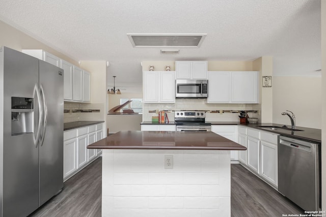 18706 Redriver, San Antonio, TX 78259 - kitchen featuring appliances with stainless steel finishes, dark countertops, dark wood-style flooring, decorative backsplash, and a textured ceiling