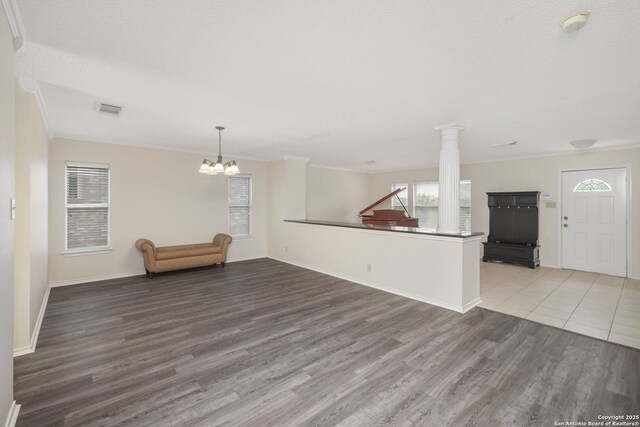 18706 Redriver, San Antonio, TX 78259 - unfurnished living room with wood finished floors, a chandelier, crown molding, and decorative columns