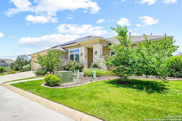 4603 Camden, San Antonio, TX 78261 - view of front facade featuring roof mounted solar panels, driveway, a front yard, an attached garage, and stone siding