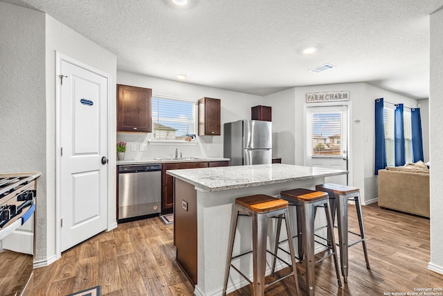 1006 Pacific Monarch, San Antonio, TX 78253 - kitchen with stainless steel appliances, a kitchen breakfast bar, light wood-style flooring, a center island, and a textured ceiling