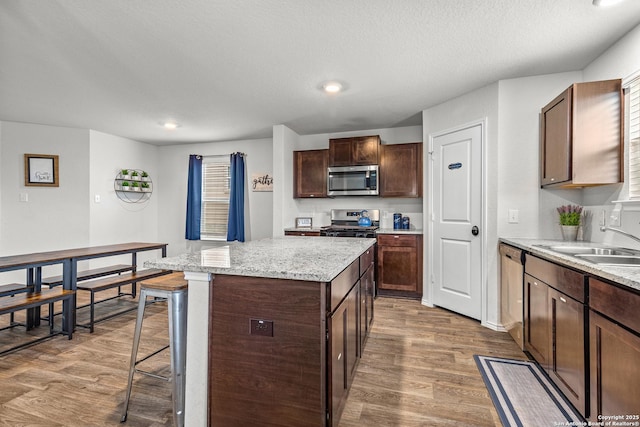 1006 Pacific Monarch, San Antonio, TX 78253 - kitchen featuring appliances with stainless steel finishes, wood finished floors, a center island, dark brown cabinets, and recessed lighting