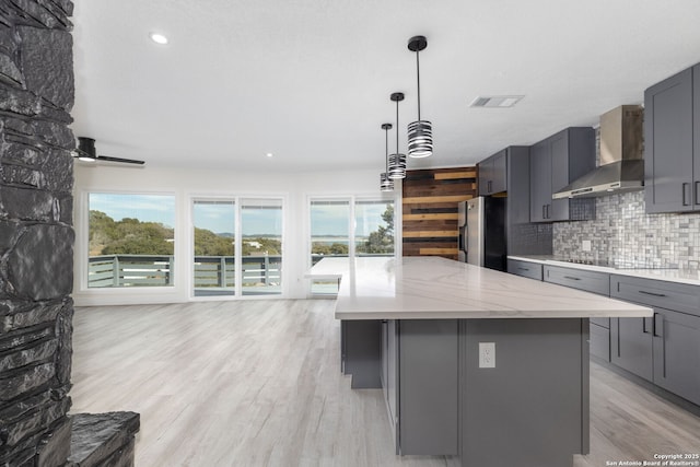 2165 Colleen Dr, Canyon Lake, TX 78133 - kitchen with wall chimney range hood, stainless steel fridge with ice dispenser, gray cabinetry, black electric stovetop, and tasteful backsplash