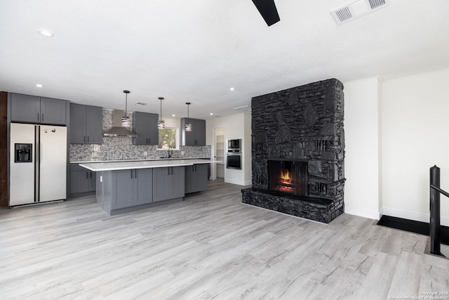 2165 Colleen Dr, Canyon Lake, TX 78133 - kitchen featuring fridge with ice dispenser, wall chimney exhaust hood, gray cabinets, light countertops, and light wood-style flooring