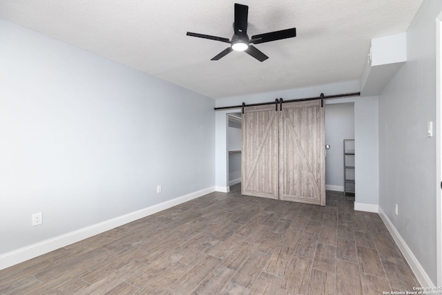 2165 Colleen Dr, Canyon Lake, TX 78133 - unfurnished bedroom with wood finished floors, a barn door, a ceiling fan, a closet, and a textured ceiling