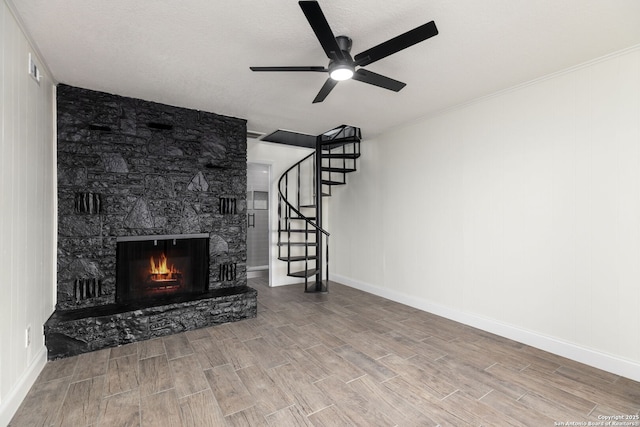2165 Colleen Dr, Canyon Lake, TX 78133 - unfurnished living room with wood finish floors, a ceiling fan, stairway, and a stone fireplace