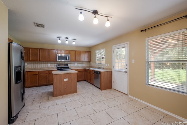 11922 Briarton Wls, San Antonio, TX 78254 - kitchen with stainless steel appliances, light countertops, decorative backsplash, a center island, and brown cabinetry