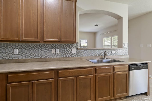 10107 Roseangel, Helotes, TX 78023 - kitchen with dishwasher, arched walkways, tasteful backsplash, light countertops, and brown cabinetry