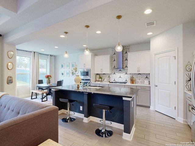 7621 Cypress, Boerne, TX 78015 - kitchen with wall chimney exhaust hood, appliances with stainless steel finishes, a breakfast bar, decorative backsplash, and a center island with sink