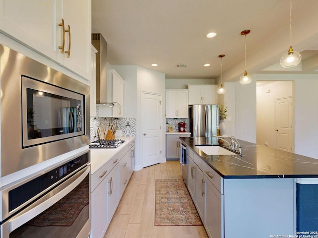 7621 Cypress, Boerne, TX 78015 - kitchen featuring stainless steel appliances, wall chimney exhaust hood, tasteful backsplash, a kitchen island with sink, and dark countertops