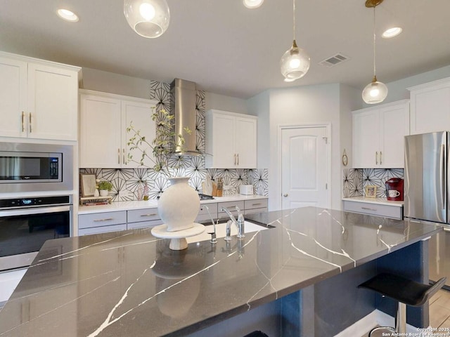 7621 Cypress, Boerne, TX 78015 - kitchen featuring stainless steel appliances, wall chimney range hood, tasteful backsplash, a breakfast bar, and recessed lighting