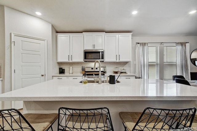 13019 Louberg, San Antonio, TX 78253 - kitchen with stainless steel microwave, decorative backsplash, a kitchen bar, white cabinetry, and recessed lighting