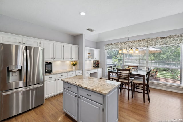 2723 Sierra Salinas, San Antonio, TX 78259 - kitchen featuring stainless steel fridge with ice dispenser, light wood-style floors, white cabinets, light stone counters, and a kitchen island