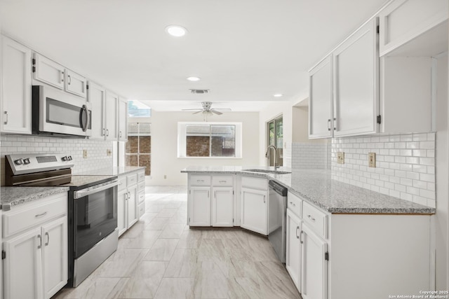 114 Crystal Cyn, Universal City, TX 78148 - kitchen featuring appliances with stainless steel finishes, a peninsula, a ceiling fan, recessed lighting, and light stone countertops