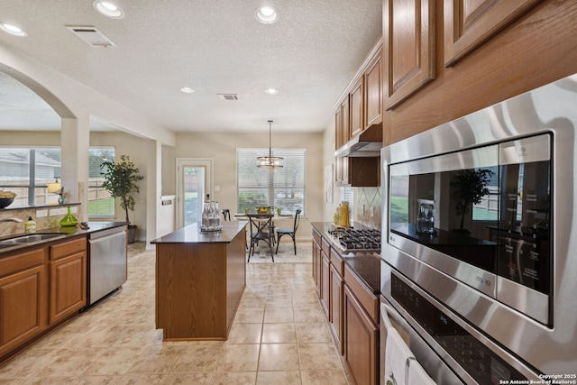 3535 Arroyo Grande, San Antonio, TX 78253 - kitchen featuring appliances with stainless steel finishes, dark countertops, a center island, arched walkways, and brown cabinetry
