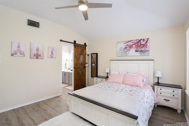 4239 Knollpass, San Antonio, TX 78247 - bedroom with a barn door, wood finished floors, vaulted ceiling, a ceiling fan, and ensuite bath