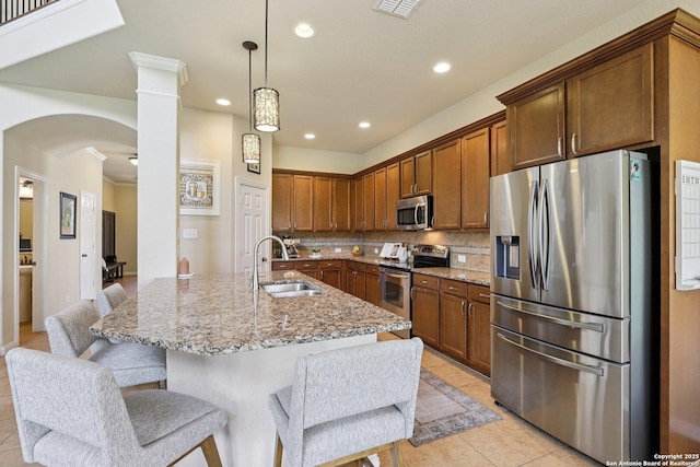 3403 Navajo Peace, San Antonio, TX 78261 - kitchen featuring appliances with stainless steel finishes, ornate columns, decorative backsplash, light stone counters, and light tile patterned flooring