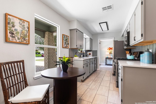 112 Meadow Way, Converse, TX 78109 - kitchen with stainless steel appliances, backsplash, gray cabinetry, and light countertops