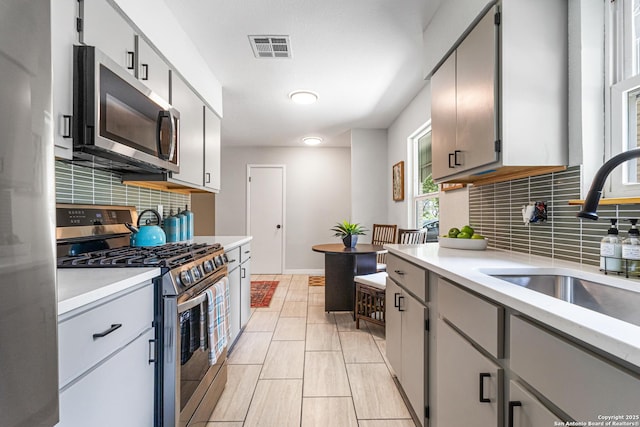 112 Meadow Way, Converse, TX 78109 - kitchen featuring stainless steel appliances, decorative backsplash, light countertops, and gray cabinetry