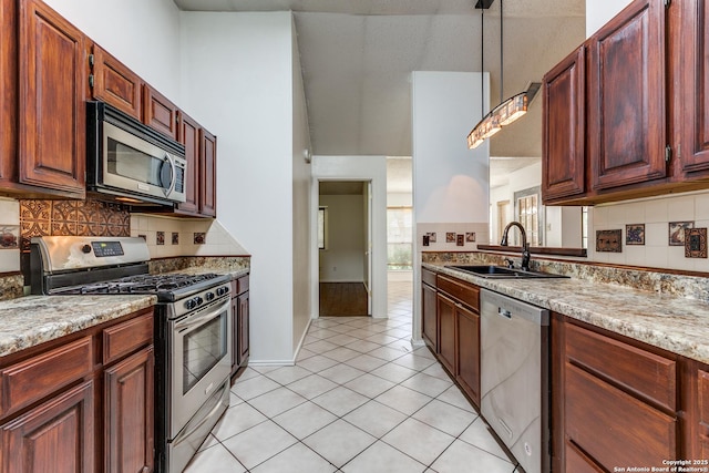 8658 Quail Whisper, San Antonio, TX 78250 - kitchen with stainless steel appliances, hanging light fixtures, backsplash, light tile patterned floors, and light stone countertops