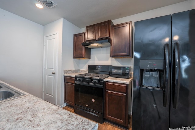 5722 Tanquil Cv, Converse, TX 78109 - kitchen with black appliances, under cabinet range hood, light wood-style floors, and light countertops