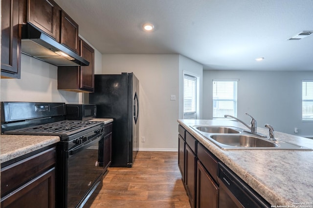 5722 Tanquil Cv, Converse, TX 78109 - kitchen featuring black appliances, under cabinet range hood, dark wood-type flooring, dark brown cabinets, and light countertops
