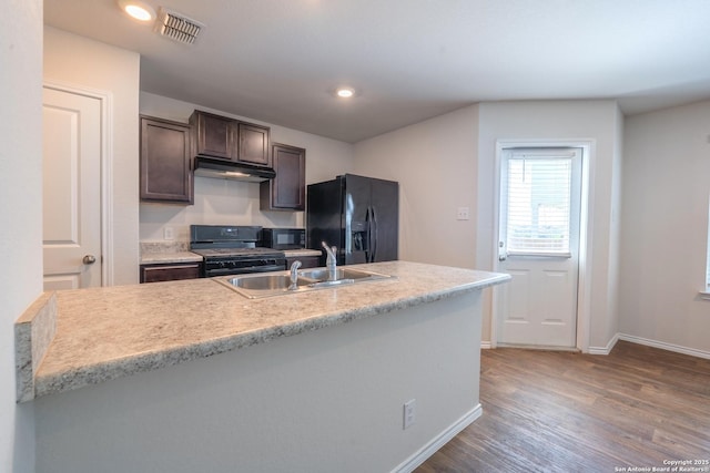 5722 Tanquil Cv, Converse, TX 78109 - kitchen with black appliances, under cabinet range hood, dark brown cabinets, wood finished floors, and light countertops