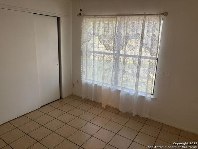 9931 Birch Fld, San Antonio, TX 78245 - unfurnished bedroom featuring light tile patterned flooring, multiple windows, and a closet